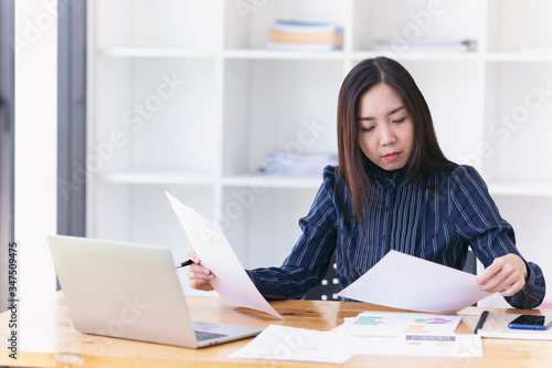 Young asian woman using laptop at home while sitting the wooden table.female hands typing on the notebook keyboard.Woman using laptop for online working at home. © Somkiat