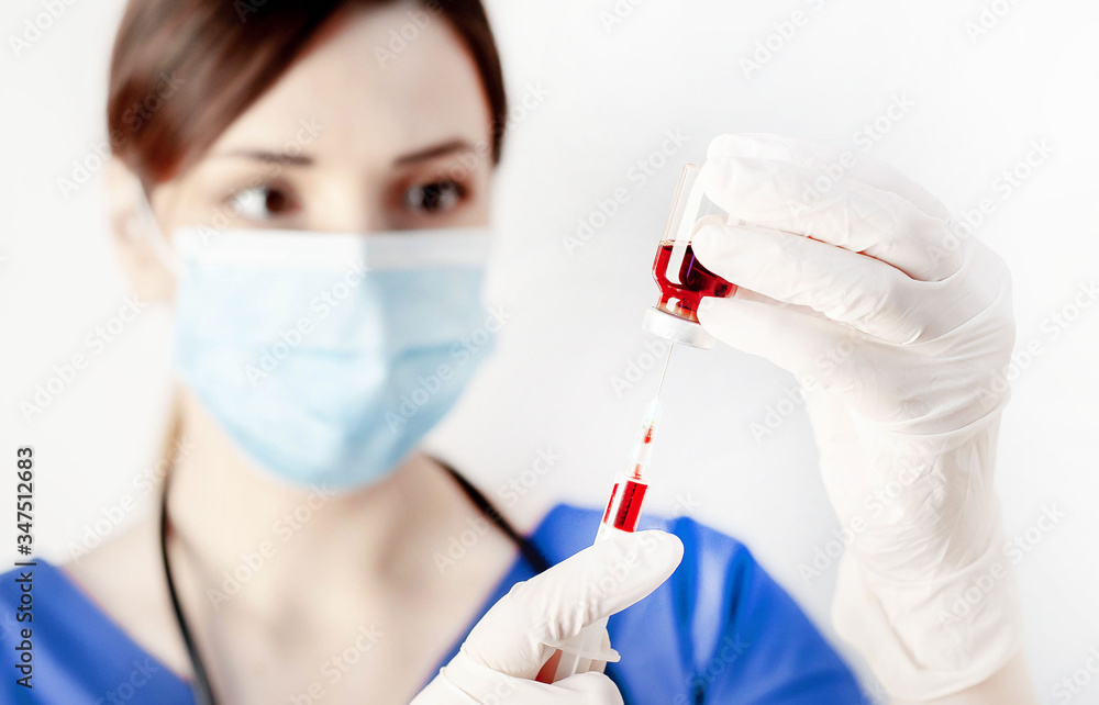 Girl doctor holds a syringe in her hand with a medicine against coronavirus on a white background with copy space for your text Girl doctor holds a syringe in her hand with a medicine against coronavirus on a white background with copy space for your text