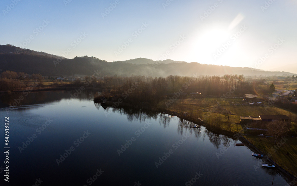 Dark water with reflections of trees, a lake in a winter sunset in the valley with some boats