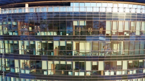 Offices in a modern high rise commercial building with glass facade. Sunset reflecting off the exterior of a corporate headquarters with suites for rent. Establishing aerial shot.