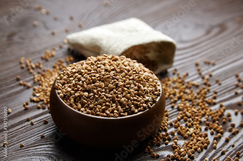 Buckwheat groats (hulled seeds) in bowl and burlap bag on wooden table © mikeosphoto