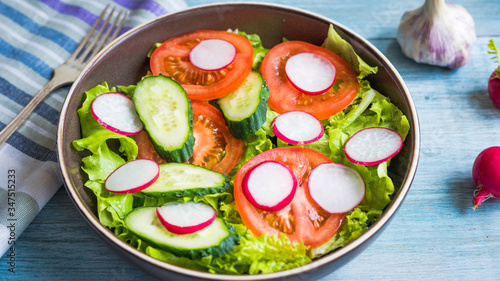 A very simple salad with fresh cucumbers, radishes, tomatoes and lettuce - homemade summer salad