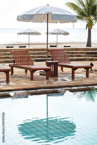 The oriental tropical beach resort. Wooden beach beds. White umbrellas at poolside with beach view.