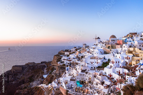 View of Oia and windmill from castle ruins at sunset, Santorini island, Cyclades, Greece