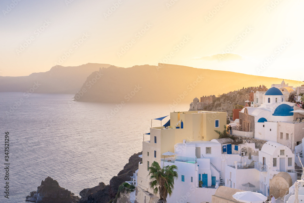 Sunset view of Oia  with blue domes,  Thirasia in the back, Santorini island, Cyclades, Greece