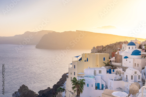 Sunset view of Oia with blue domes, Thirasia in the back, Santorini island, Cyclades, Greece
