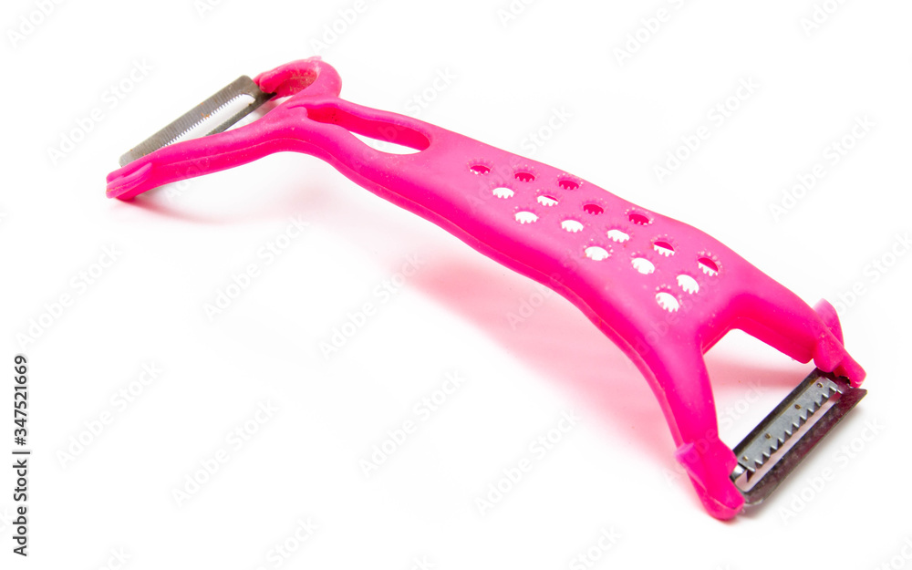 Pink peeler on a white background. Knife, peel for vegetables and fruits on a white drain Pink peeler on a white background. Knife, peel for vegetables and fruits on a white drain