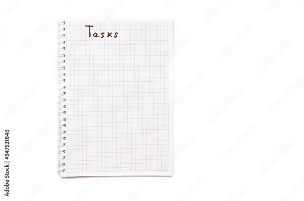 Notebook with a spiral in a cage on a white background. Above in a notebook is written tasks with a black marker, pen. Notepad top view. Notepad Part Notebook with a spiral in a cage on a white background. Above in a notebook is written tasks with a black marker, pen. Notepad top view. Notepad Part