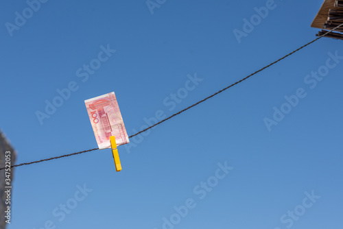 Сhina yuan (CNY) with a clothespin on a rope on the blue sky background. Money of south-east Asia. Concept