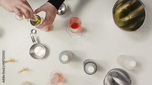 Girl pours oil in reagent tubes, making cosmetics in lab. Topdown shot