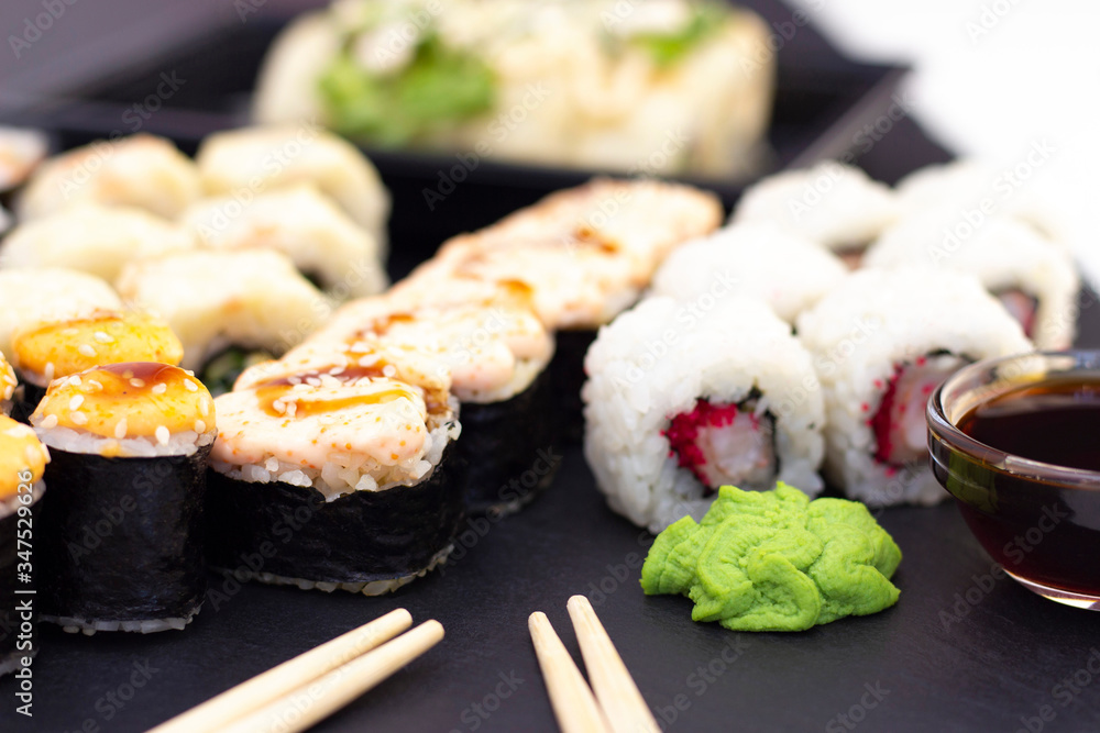 Set of rolls, wasabi, sauce and wooden sticks on a stone black table. Set of rolls, wasabi, sauce and wooden sticks on a stone black table.