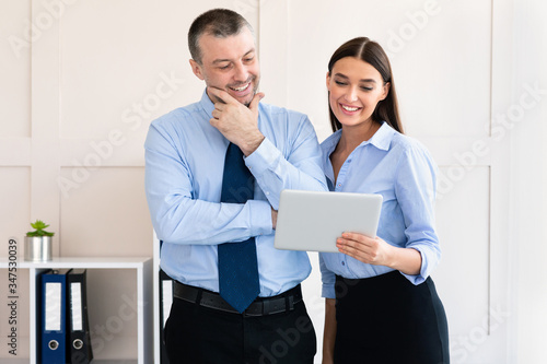 Businesswoman Showing Digital Tablet To Coworker Man Standing In Office