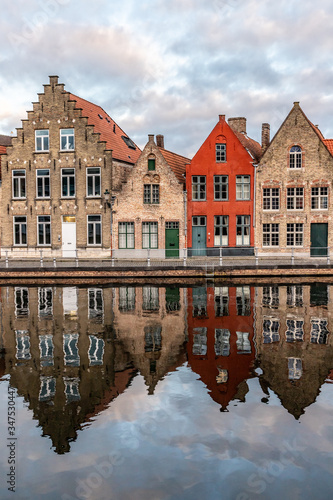 Buildings with reflections around channels in Bruges at sunset