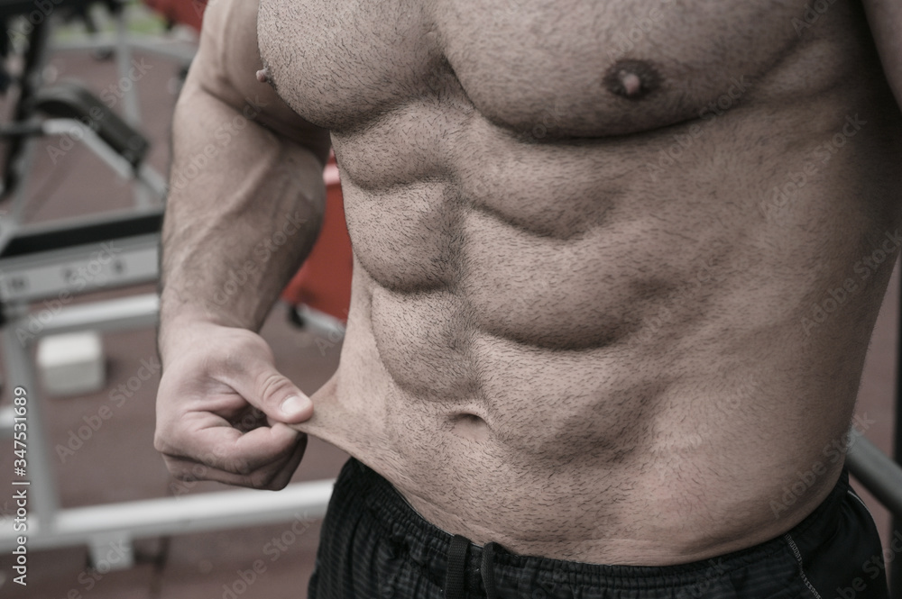 Foto Stock body fat weight loss sport nutrition concept on strong young man  with perfect body physique abdominal muscle and thin skin | Adobe Stock