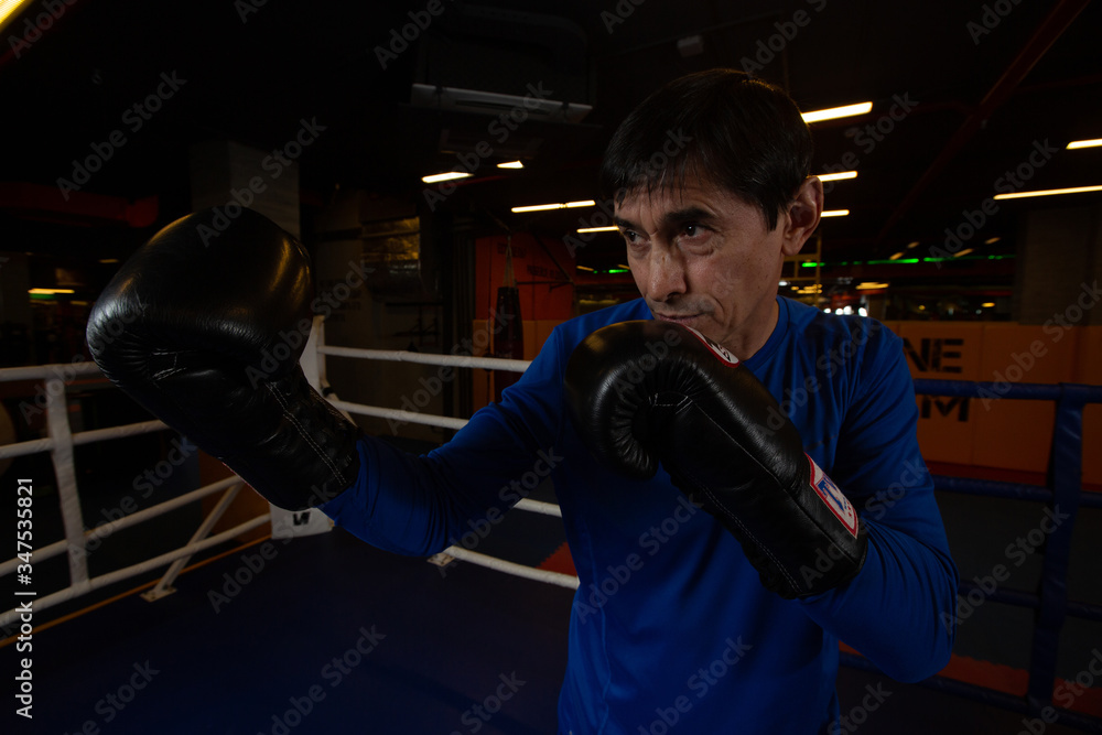 A boxing coach stands in the ring wearing black gloves ready to spar. Concept of sports motivation