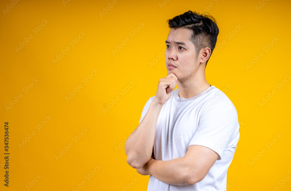Young Asian man isolated on yellow background looking sideways with doubtful and skeptical expression. Young Asian man isolated on yellow background looking sideways with doubtful and skeptical expression.