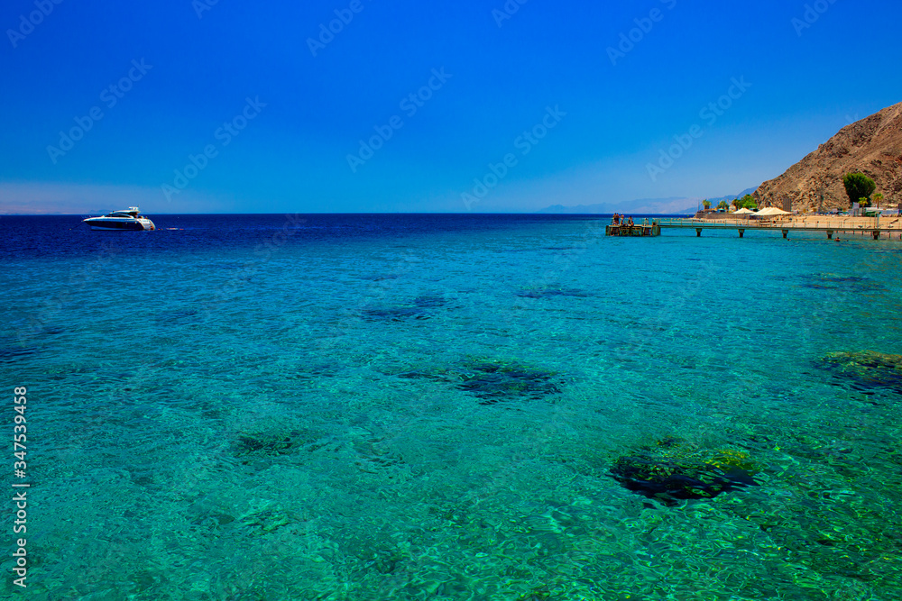 Red sea shore line coral beach summer vacation destination landscape scenic view cruise yacht on a water and pier with people Middle East place
