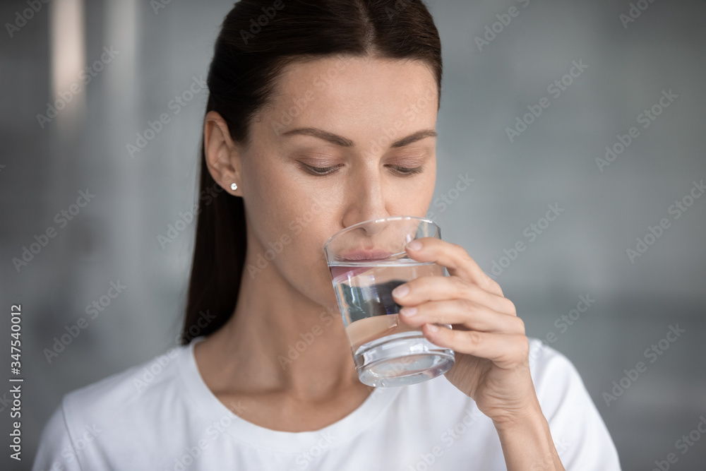 Woman drinks still water close up portrait. Quench thirst, water balance and weight control, caring of skin and body, hangover relief, body refreshment, energy recovery, dehydration prevention concept Woman drinks still water close up portrait. Quench thirst, water balance and weight control, caring of skin and body, hangover relief, body refreshment, energy recovery, dehydration prevention concept
