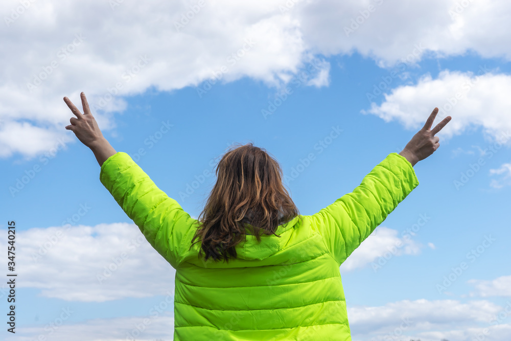 Back view. Portrait of a woman stretching her arms outdoors towards the sky. Back view. Portrait of a woman stretching her arms outdoors towards the sky.