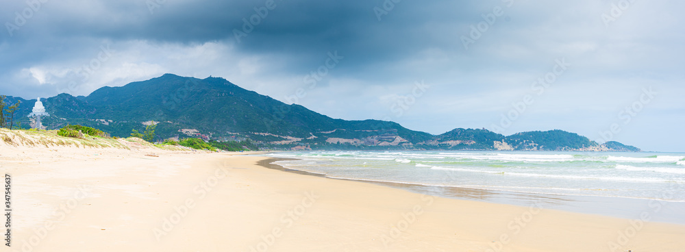 Secluded tropical beach turquoise transparent water dramatic clouds on mountains, Quy Nhon Vietnam central coast travel destination, desert white sand beach no people