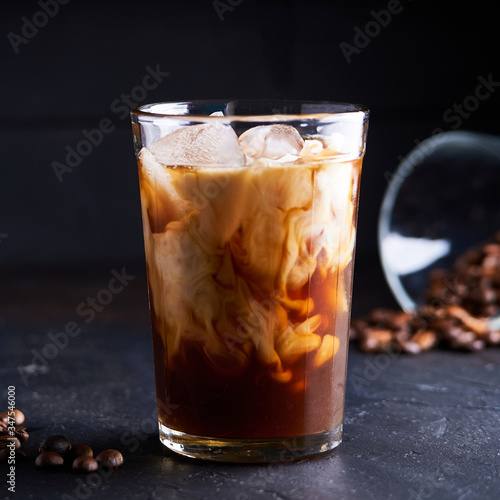 Tasty ice coffee with milk , cold drink in glass on dark background
