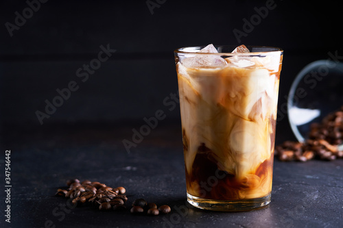 Tasty ice coffee with milk , cold drink in glass on dark background Copy space