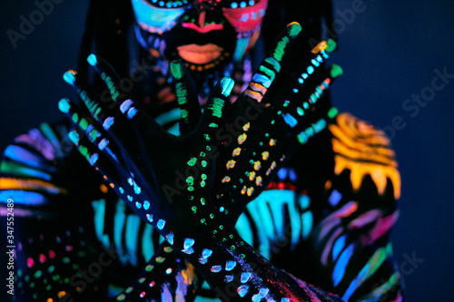 portrait of muscular young man in bright blacklight bodyart glowing in darkness. fluorescent  luminescent body art