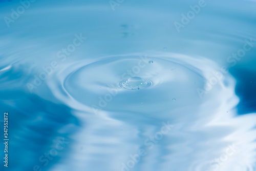 Water drops splash and circle reflextion background.Close up fresh water drops falling into the water and ripples of light blue.