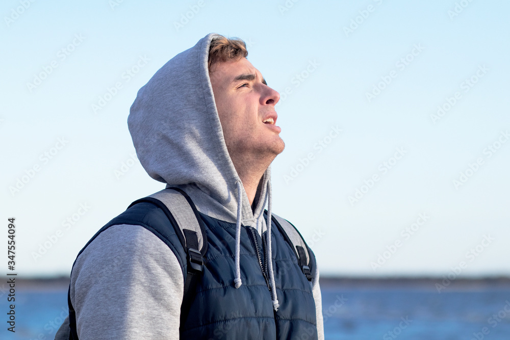 Sad handsome guy on the bay and sea suffering. Young man pondering, crying meditating outdoors. Sad handsome guy on the bay and sea suffering. Young man pondering, crying meditating outdoors.