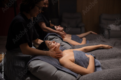 professional masseurs doctors doing anti-aging massage to female clients. beautiful women enjoys face and neck massage in spa salon