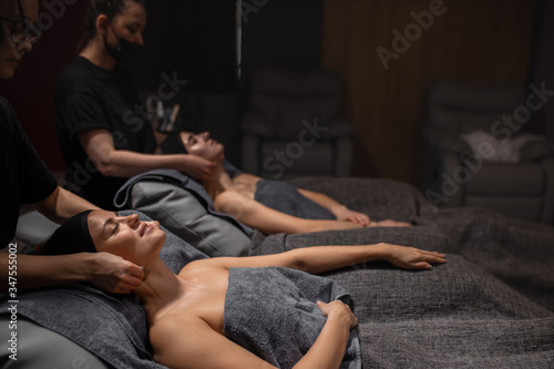 beautiful caucasian healthy women relaxing on massage table, body care in spa salon, massage on face, head, neck, shoulders