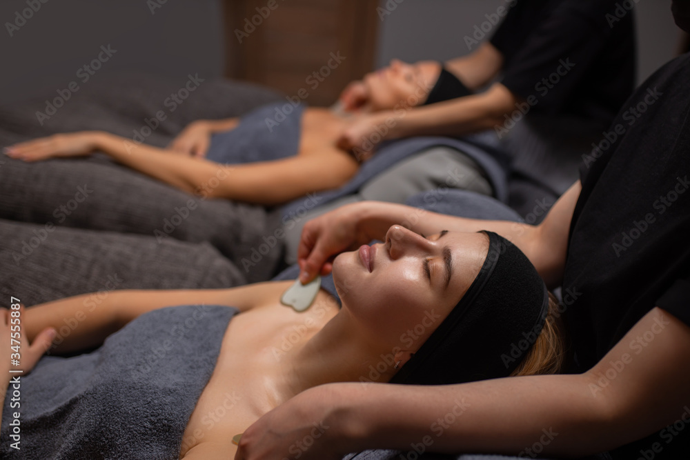young and beautiful caucasian woman get massage on shoulders and neck with the use of cosmetic tools in luxury spa salon