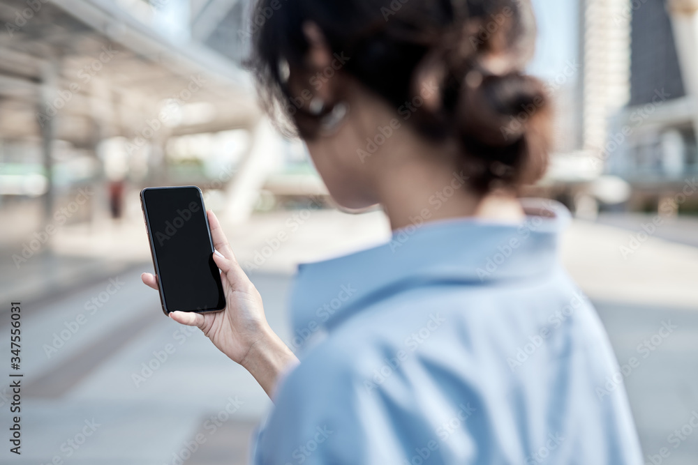 A beautiful Asian business woman is looking at her smartphone.