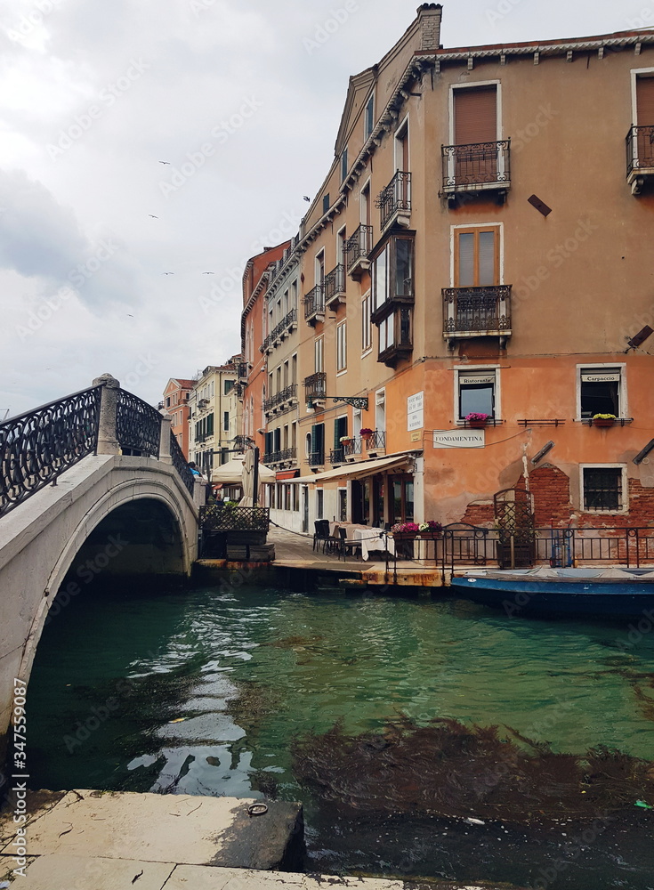 The bridge over venetian canal after the rain, ancient architecture of Italy