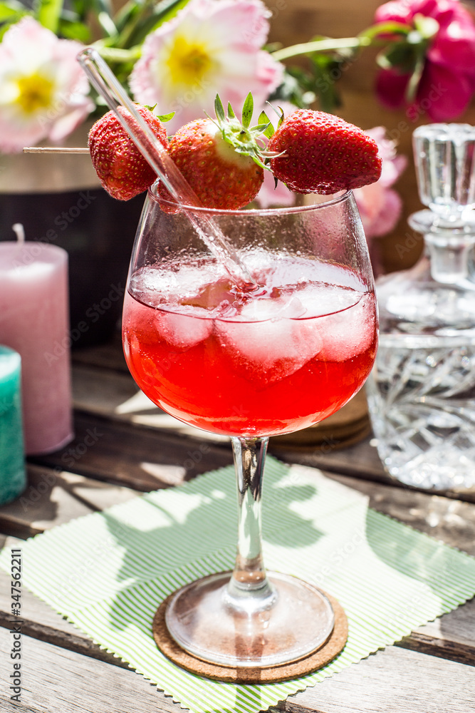 Strawberry Cocktail on a wooden table in the sun with flowers and candles Strawberry Cocktail on a wooden table in the sun with flowers and candles