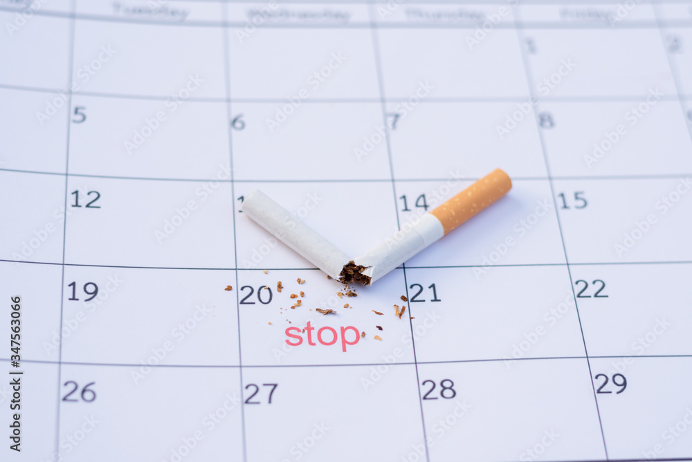 Time to quit smoking. Cigarette butts on the calendar. Concept of choosing a day to quit smoking Time to quit smoking. Cigarette butts on the calendar. Concept of choosing a day to quit smoking