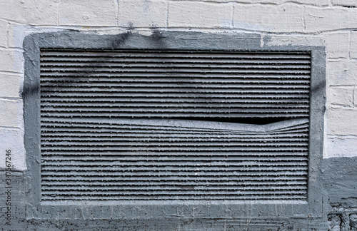 Gray iron ventilation grill on a white and gray brick wall. Background, wallpaper, texture.