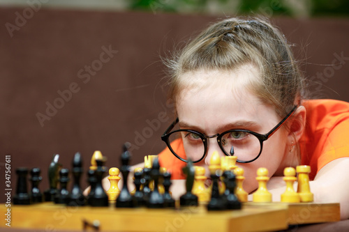 Portrait Caucasian Little girl playing chess at home during quarantine. Early childhood development