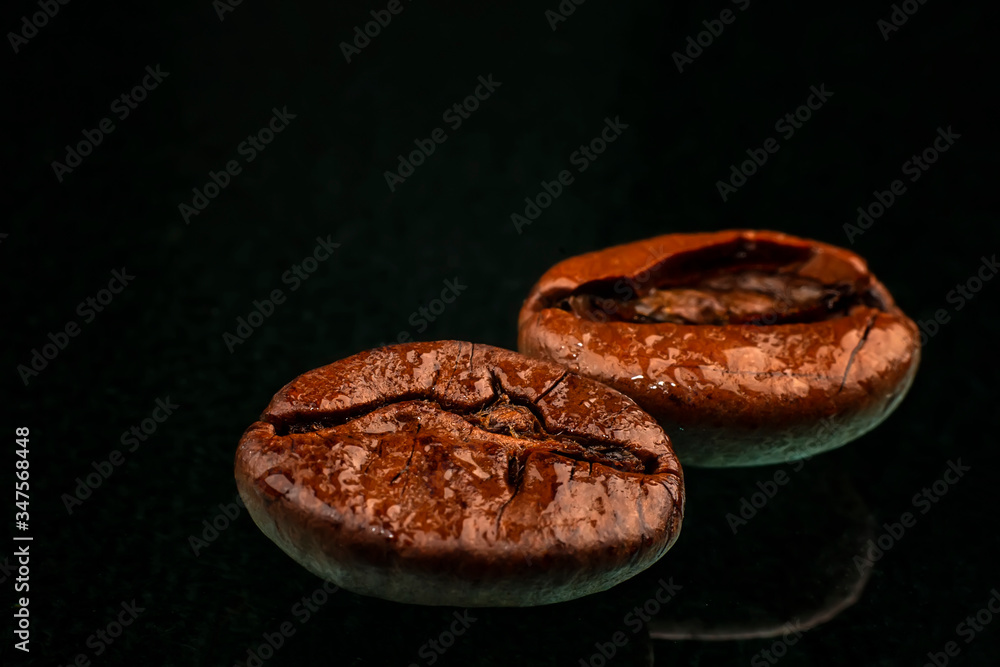 a coffee beans macro shot with water drops and reflection. Black background a coffee beans macro shot with water drops and reflection. Black background