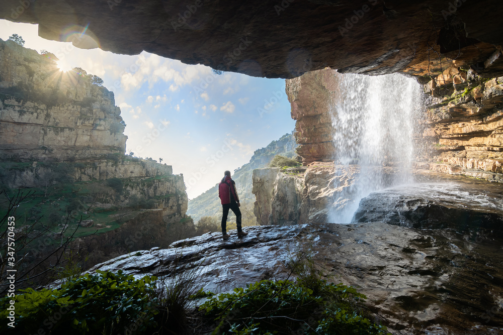 hombre mirando la naturaleza desde cueva con cascada foto de Stock | Adobe  Stock