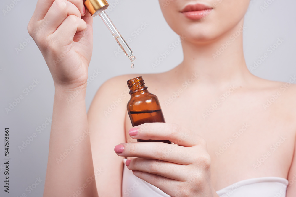 Fototapeta premium Massage therapist pouring essential oil onto hand in spa salon woman hand hold a spuit, dropping pipet, medicine pipette. Girl hand