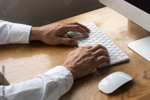 Men's hands, keyboard and mouse on the wooden table