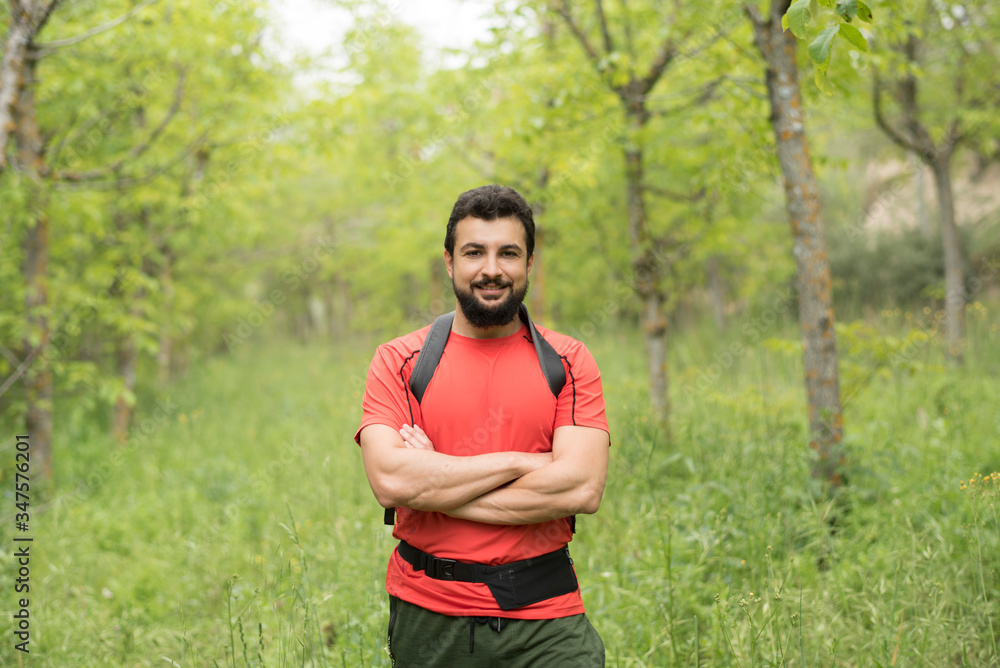 Attractive bearded man walks through the woods hiking with his backpack Attractive bearded man walks through the woods hiking with his backpack