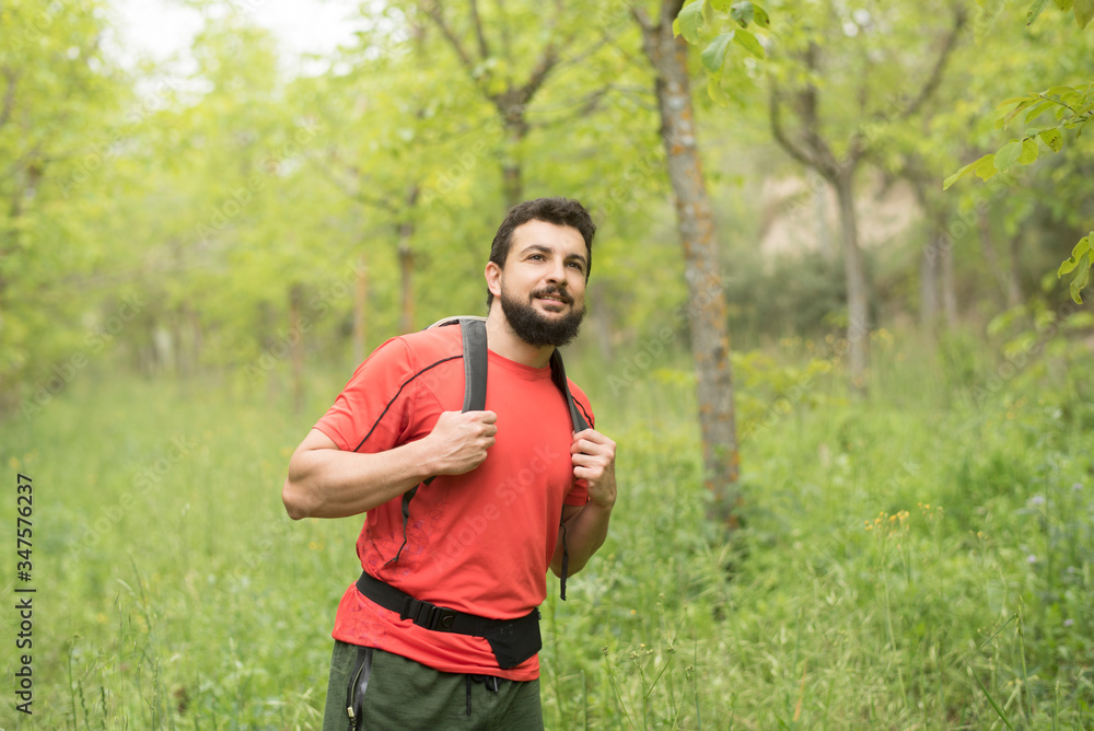 Attractive bearded man walks through the woods hiking with his backpack Attractive bearded man walks through the woods hiking with his backpack