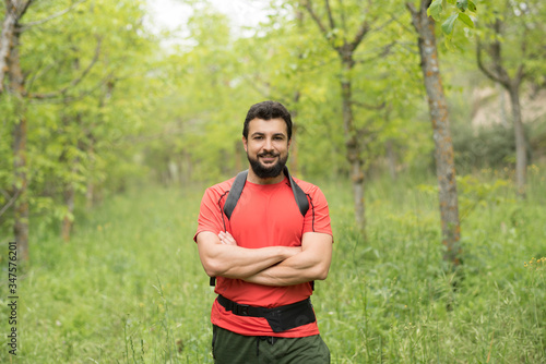 Attractive bearded man walks through the woods hiking with his backpack