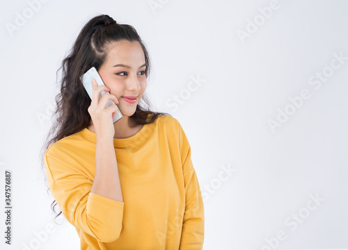 Asian woman using phone call wearing a yellow sweater isolated on white background.