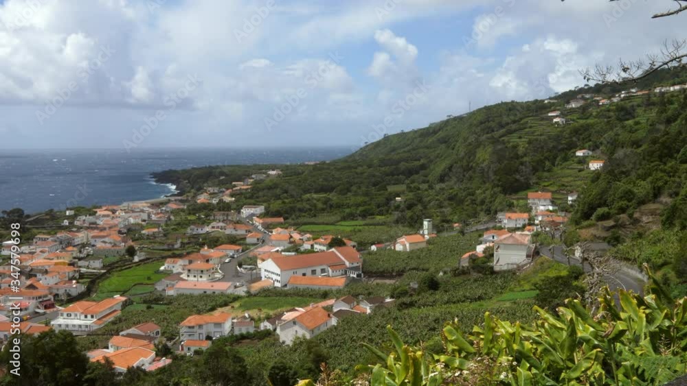Houses at coastal town by sea against cloudy sky during sunny day - Azores, Portugal Houses at coastal town by sea against cloudy sky during sunny day - Azores, Portugal