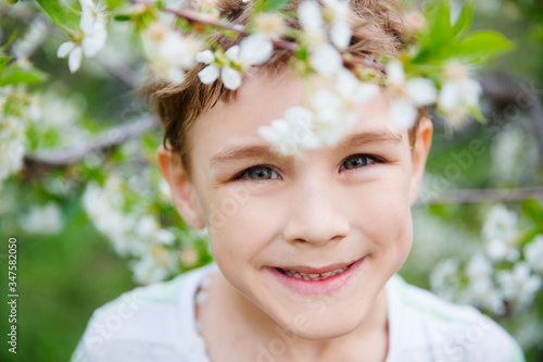 Child boy outdoors in a beautiful spring garden. Kid with flower cherry tree garden. Summertime
