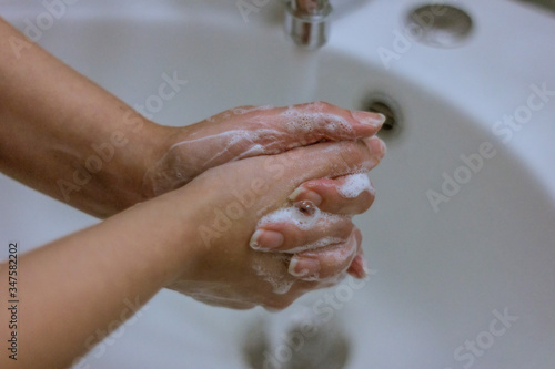 To prevent a coronavirus pandemic  a girl washes her hands with soap and water  proper washing and handling of an antiseptic will protect against the virus.