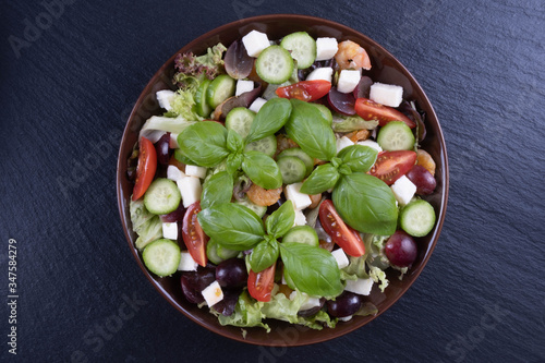 salad of slices of cheese, grapes, cucumbers, tomatoes and basil in a plate